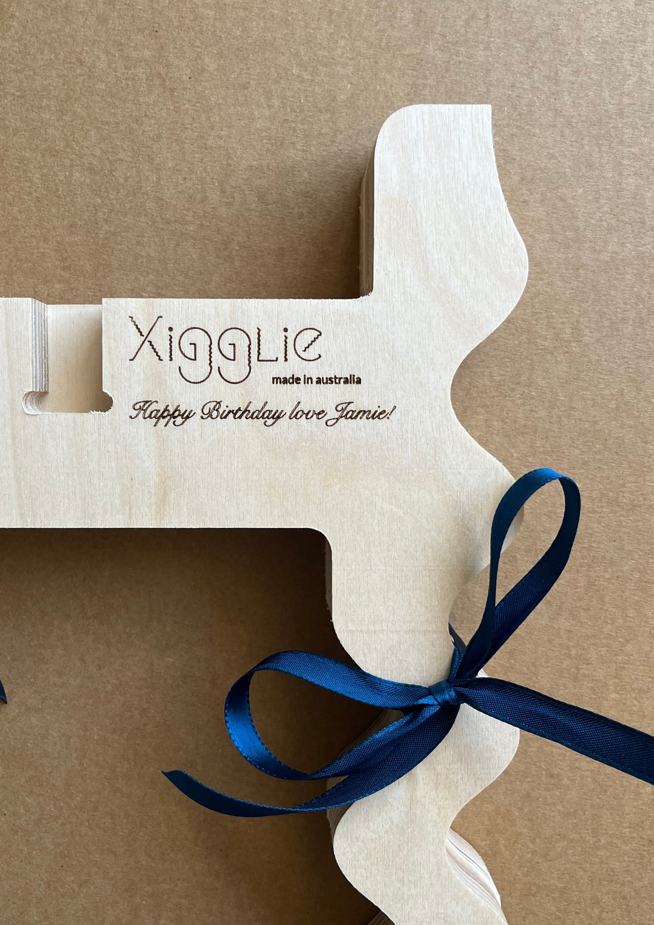 Close up view of Xigglie product in Birch plywood, with personalised message laser engraved into wood surface.