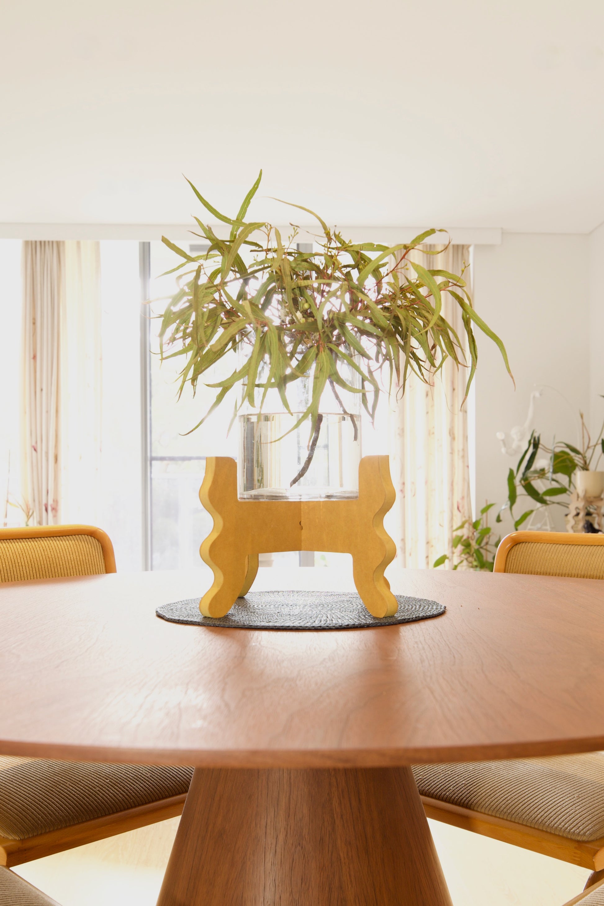 A Xigglie Saffron Low-Rider Plant Stand. Australian designed and made in yellow moisture-resistant MDF. Supporting vase with native foliage in table centre.