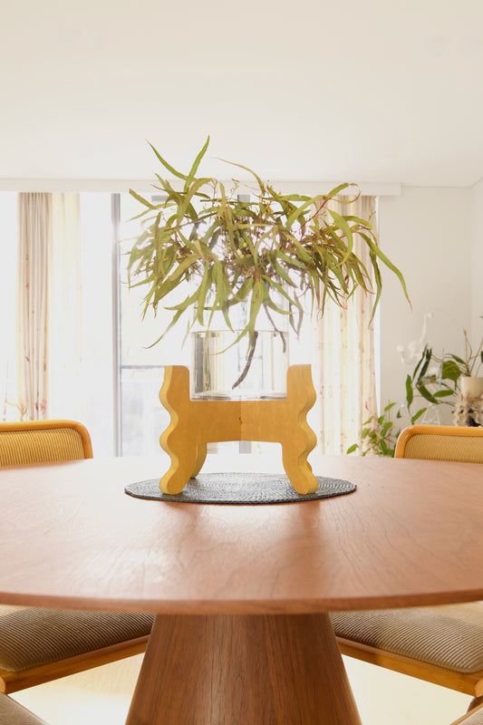A Xigglie Saffron Low-Rider Plant Stand. Australian designed and made in yellow moisture-resistant MDF. Supporting vase with native foliage in table centre.