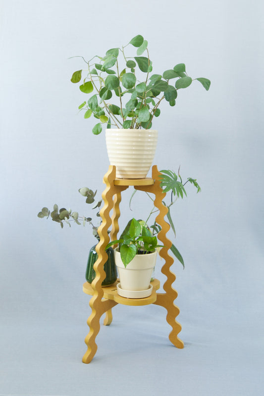 A Xigglie Saffron Two-Up Plant Stand. Australian designed and made in yellow moisture-resistant MDF. Supporting plants in pots.