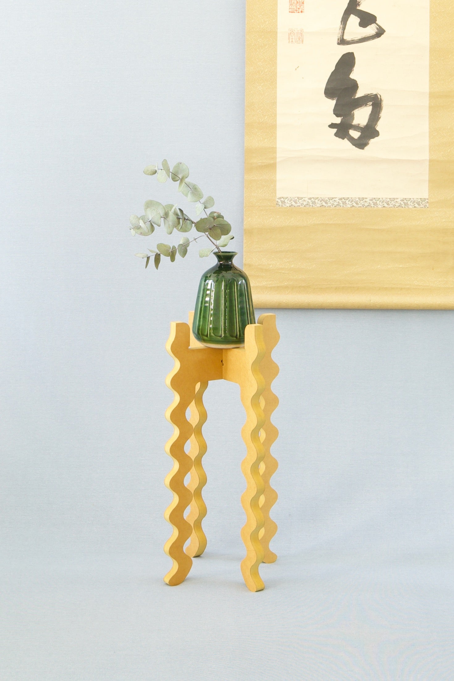 A Xigglie Saffron Tallboy Skinny Plant Stand. Australian designed and made in yellow moisture-resistant MDF. Supporting a green vase.