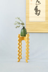 A Xigglie Saffron Tallboy Skinny Plant Stand. Australian designed and made in yellow moisture-resistant MDF. Supporting a green vase.