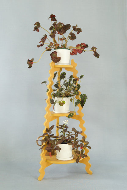 A Xigglie Saffron Threezy Plant Stand. Australian designed and made in yellow moisture-resistant MDF. 3 tiers supporting plants in pots.