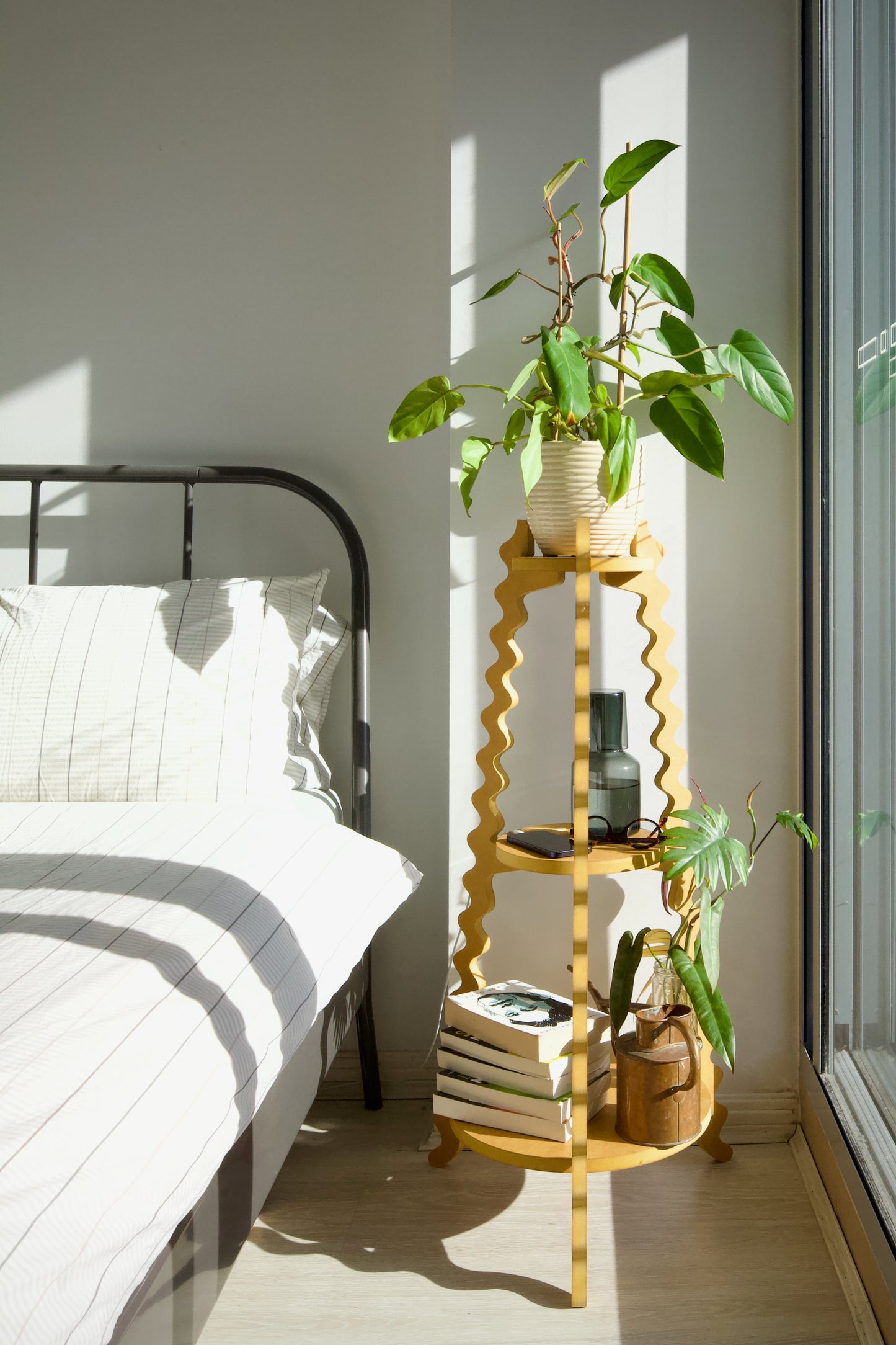 A Xigglie Saffron Threezy Plant Stand. Australian designed and made in yellow moisture-resistant MDF. 3 tiers supporting plants in pots, books, and objects by bedside.