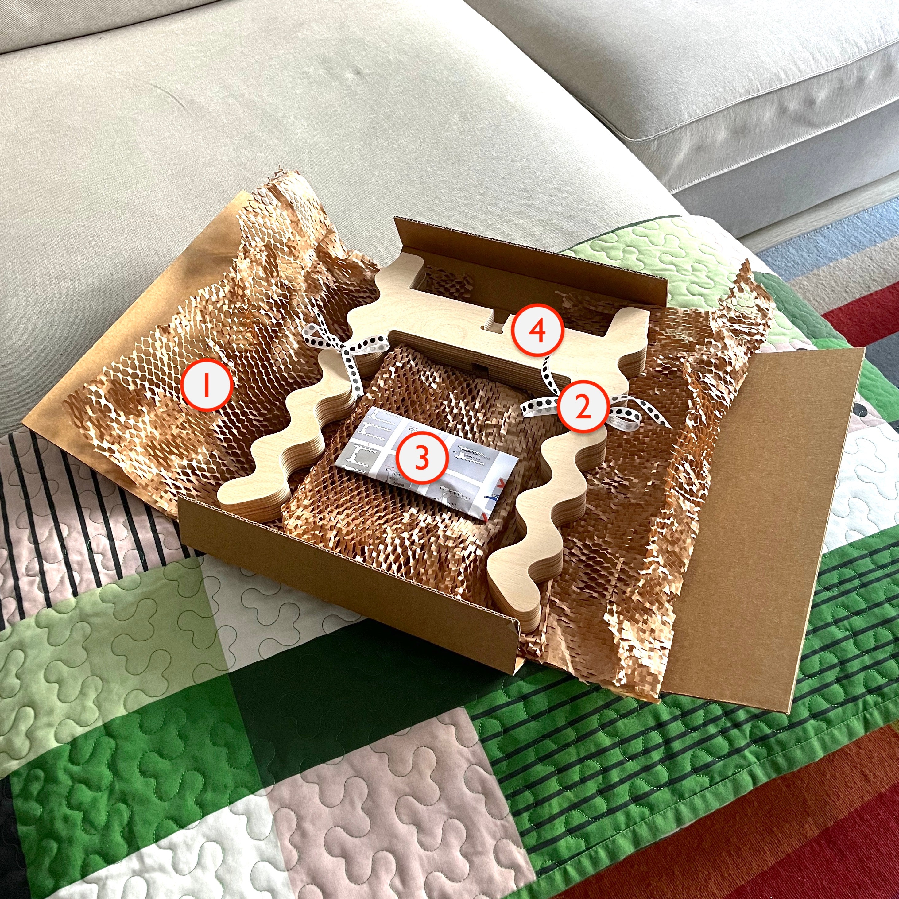 Inside view of open Xigglie package. Showing Xigglie product tied with salvaged decorative ribbon and wrapped in recycled honeycomb packing paper, with assembly instructions and complimentary handsoap bar included.